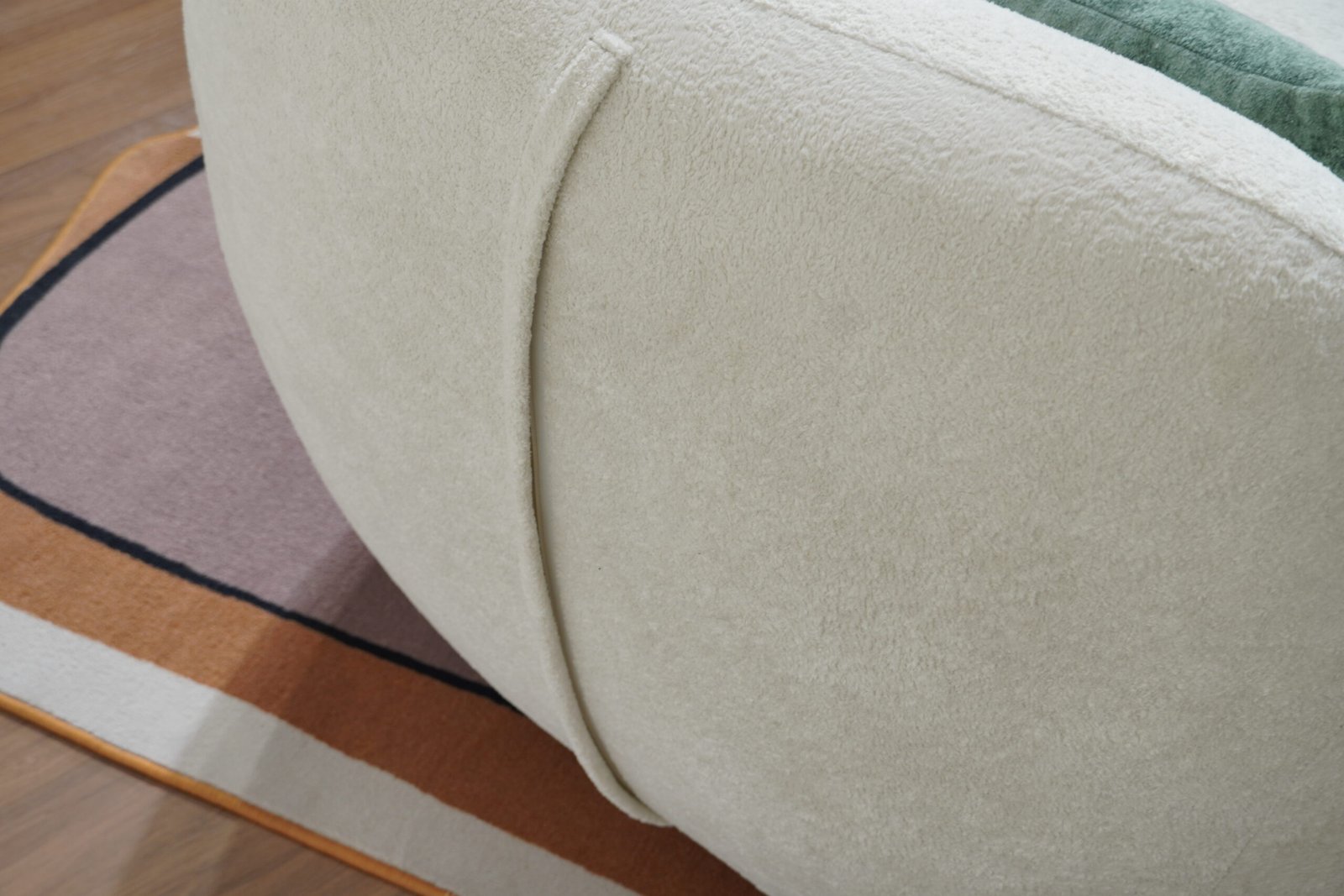 Close-up of textured white fabric and curved stitching on Nestory Sofa chair